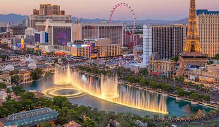 Las Vegas cityscape at dusk with illuminated Bellagio Fountains and famous landmarks.